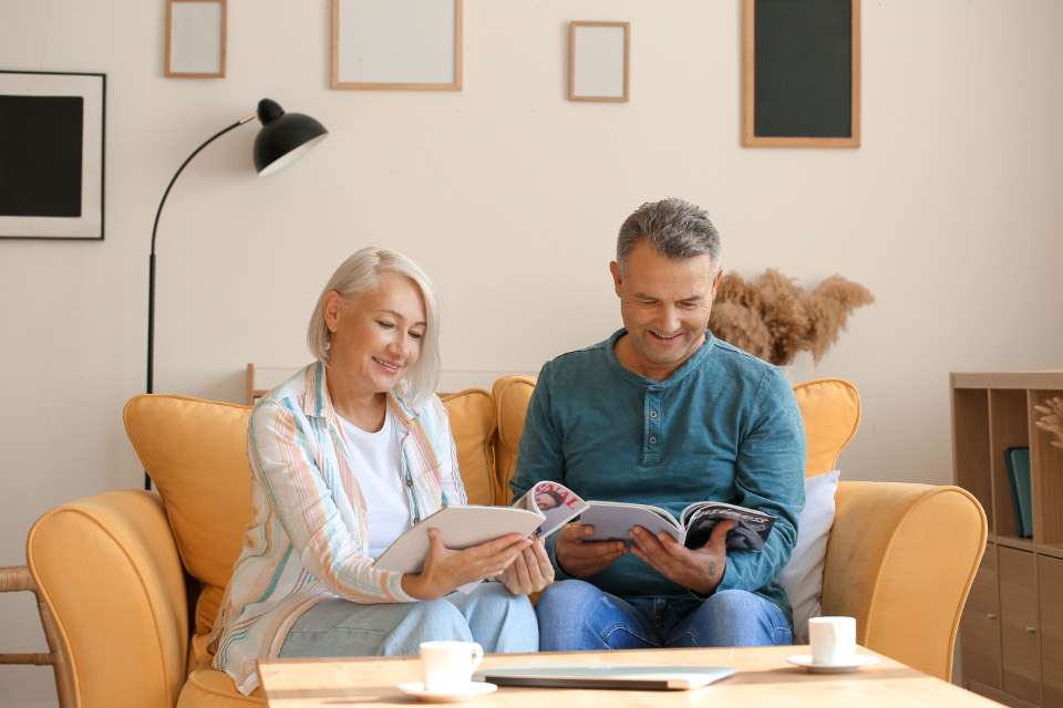 Two people reading side by side at home